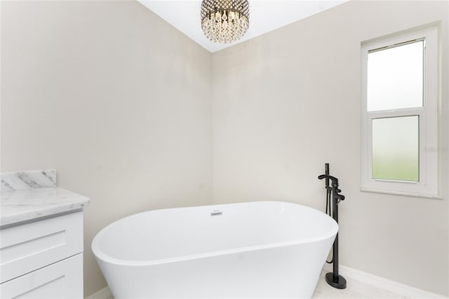 bathroom featuring a tub to relax in, tile patterned floors, vanity, and an inviting chandelier