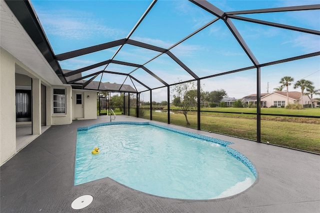 view of pool featuring a lawn, glass enclosure, and a patio area