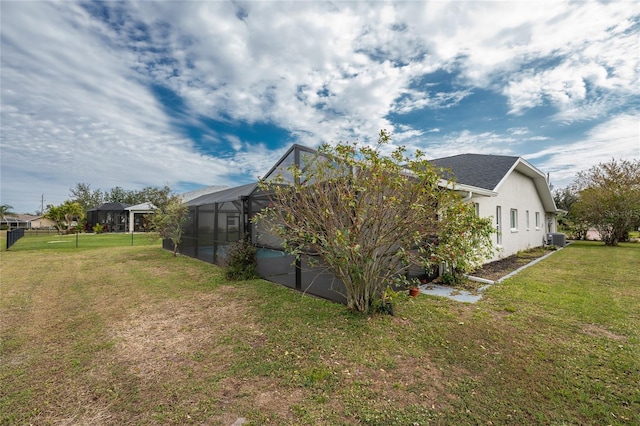 view of home's exterior with glass enclosure, cooling unit, and a lawn