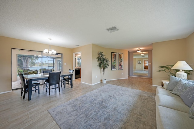 living room featuring a textured ceiling, light hardwood / wood-style floors, and an inviting chandelier