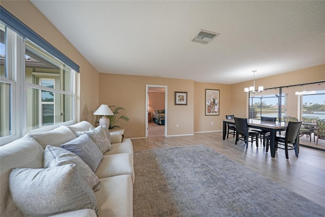 living room with a textured ceiling, light hardwood / wood-style flooring, and a notable chandelier