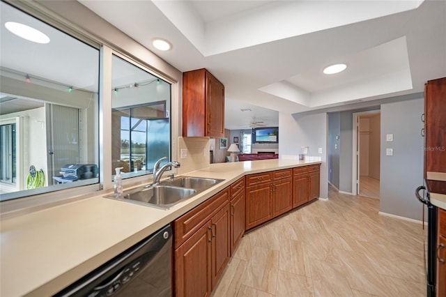 kitchen featuring ceiling fan, dishwasher, sink, kitchen peninsula, and a tray ceiling