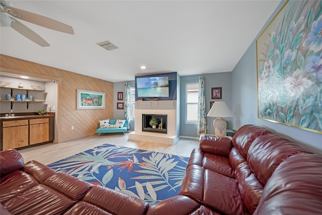 living room with ceiling fan, light hardwood / wood-style floors, and wooden walls