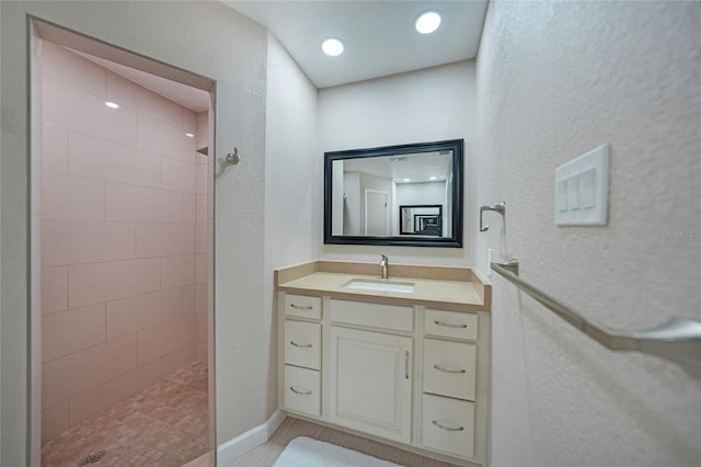 bathroom with tiled shower and vanity