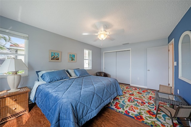 bedroom featuring wood-type flooring, a textured ceiling, a closet, and ceiling fan