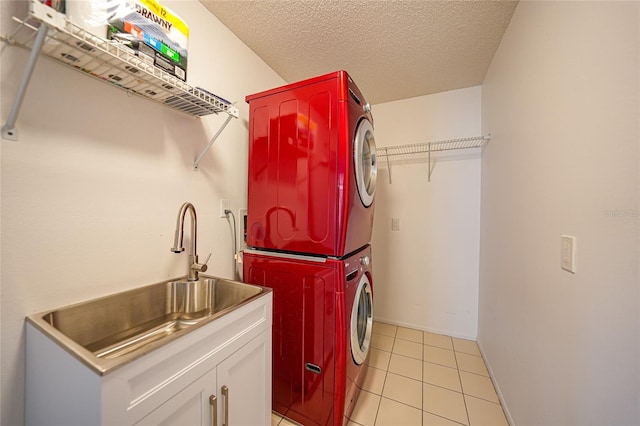 washroom with cabinets, sink, stacked washing maching and dryer, a textured ceiling, and light tile patterned floors