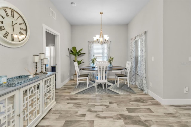 dining area with light hardwood / wood-style floors and a notable chandelier