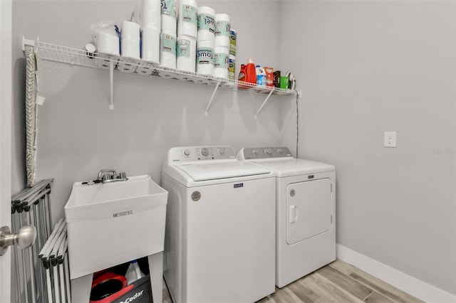 laundry area with washing machine and dryer, sink, and light hardwood / wood-style floors