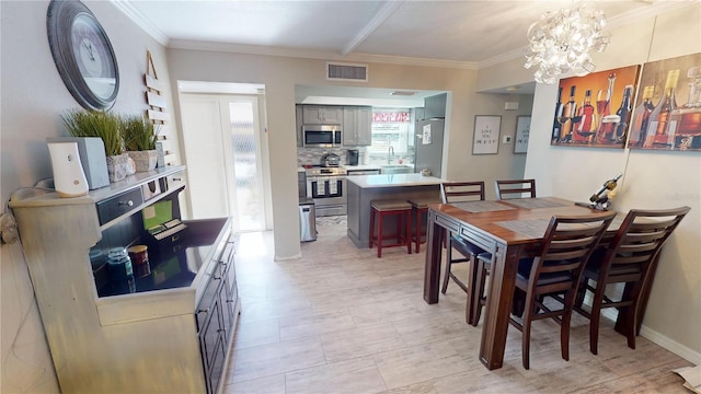 dining room featuring a notable chandelier, ornamental molding, and sink