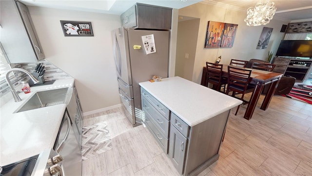 kitchen featuring crown molding, sink, decorative light fixtures, stainless steel refrigerator, and a chandelier