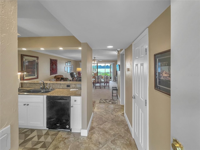 kitchen featuring dishwasher, white cabinets, sink, crown molding, and light stone counters