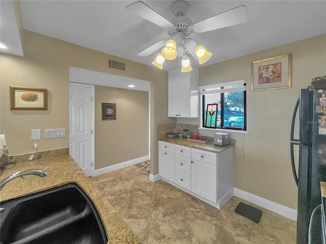 kitchen featuring black refrigerator, white cabinetry, ceiling fan, and sink