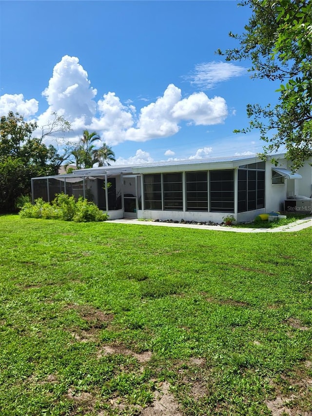 back of house featuring a lawn and a sunroom