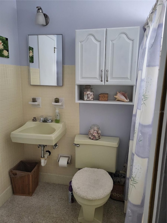 bathroom with sink, tile walls, and toilet