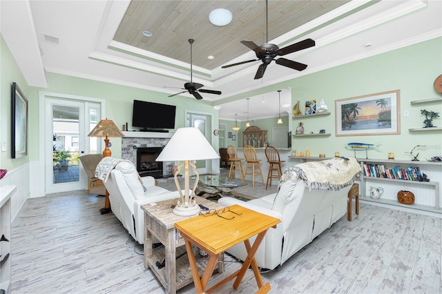 living room featuring a fireplace, ornamental molding, light hardwood / wood-style flooring, a tray ceiling, and wood ceiling