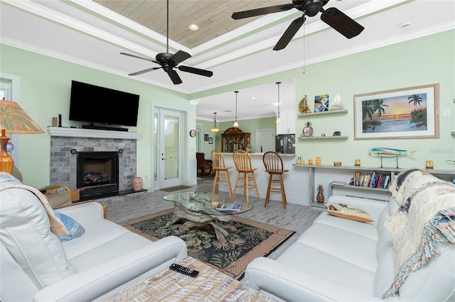 living room with hardwood / wood-style flooring, a tray ceiling, a fireplace, ornamental molding, and wooden ceiling