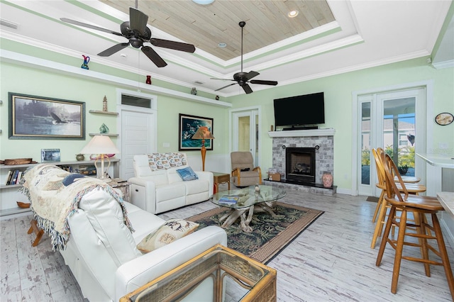 living room with wooden ceiling, a fireplace, ornamental molding, light wood-type flooring, and a tray ceiling