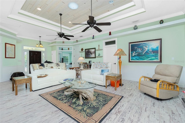 living room featuring light wood-type flooring, a tray ceiling, ceiling fan with notable chandelier, ornamental molding, and wooden ceiling