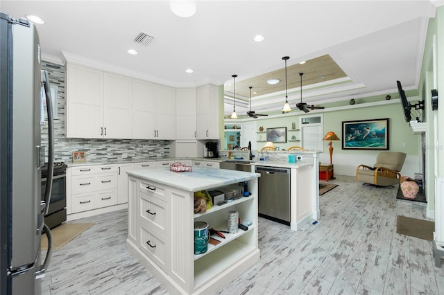 kitchen featuring stainless steel appliances, white cabinetry, kitchen peninsula, hanging light fixtures, and a kitchen island