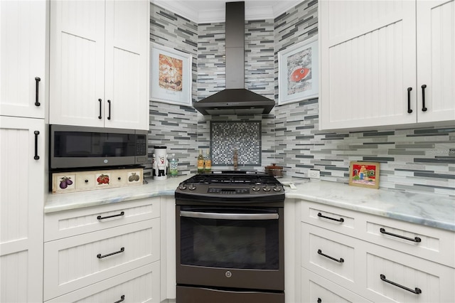 kitchen featuring gas range oven, white cabinetry, wall chimney exhaust hood, and decorative backsplash