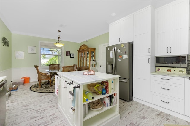 kitchen featuring a center island, white cabinetry, light wood-type flooring, hanging light fixtures, and appliances with stainless steel finishes