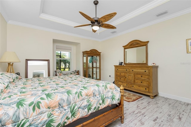 bedroom featuring ceiling fan, light hardwood / wood-style flooring, a raised ceiling, and crown molding