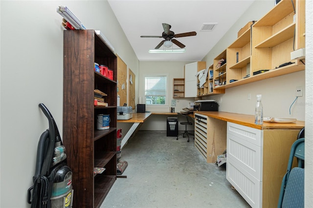 home office featuring built in desk, ceiling fan, and concrete floors