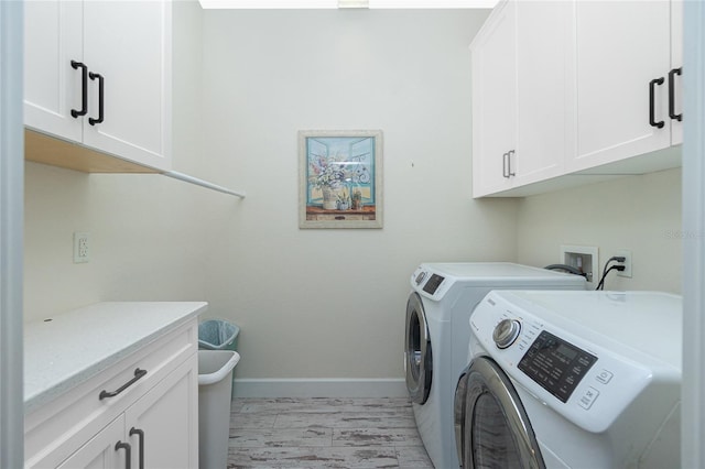 clothes washing area featuring washer and dryer and cabinets