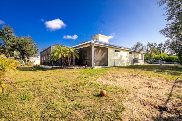 rear view of property with a lanai and a yard