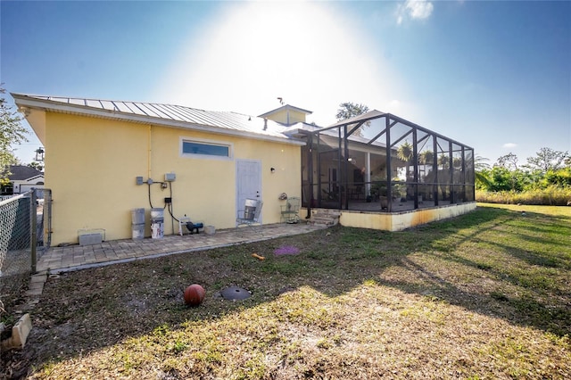 back of property with a patio area, glass enclosure, and a yard