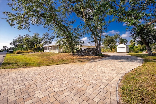 view of front of home featuring an outbuilding, covered porch, a front lawn, and a garage