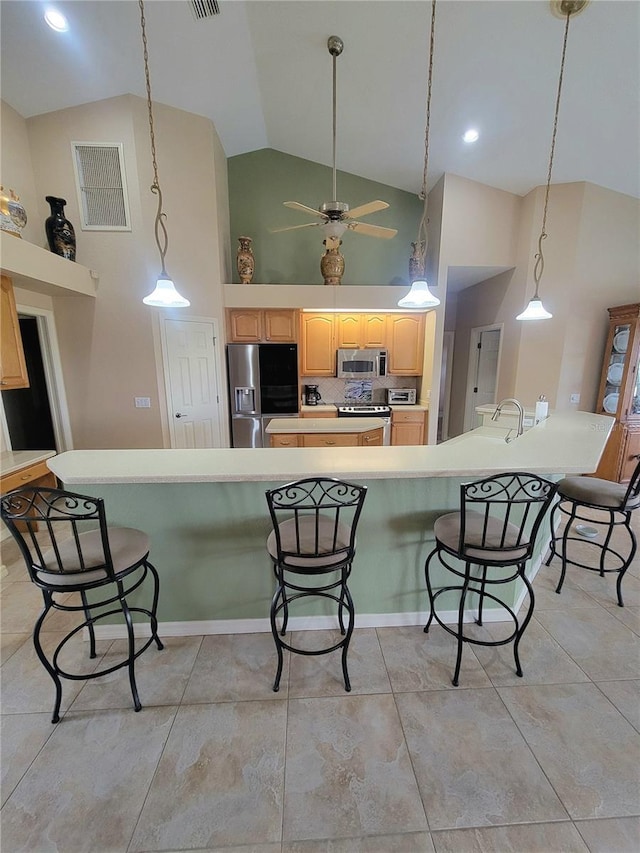 kitchen featuring ceiling fan, tasteful backsplash, high vaulted ceiling, light brown cabinetry, and appliances with stainless steel finishes