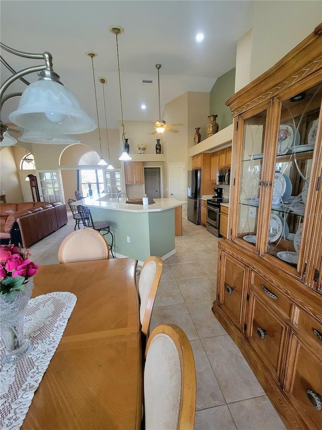 tiled dining room featuring ceiling fan, sink, and vaulted ceiling