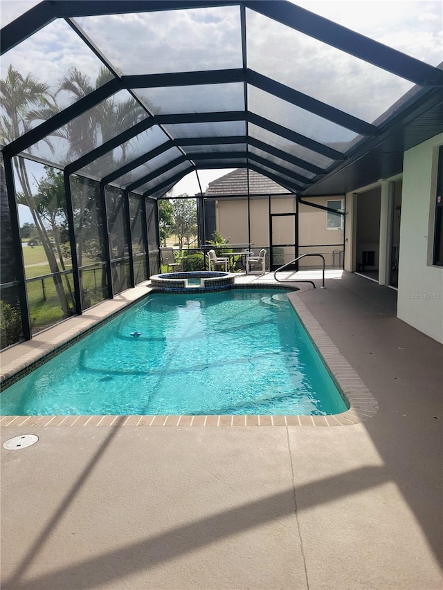 view of pool featuring glass enclosure, a patio area, and an in ground hot tub