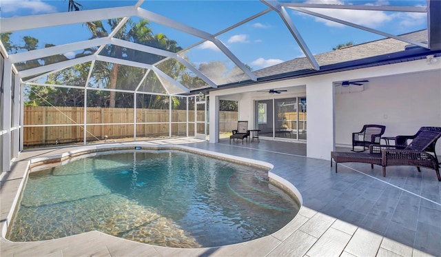 view of pool with a patio area, ceiling fan, and glass enclosure