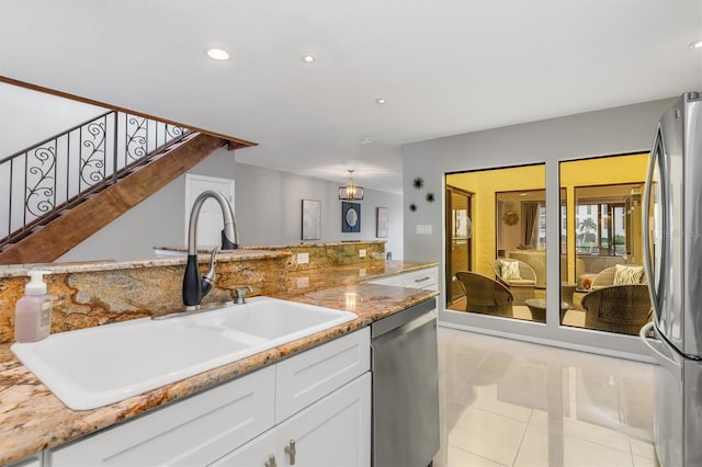 kitchen featuring sink, light stone countertops, appliances with stainless steel finishes, light tile patterned flooring, and white cabinetry