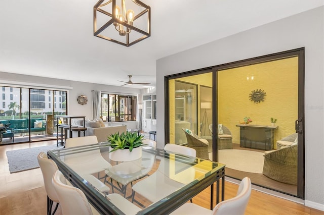 dining area featuring light wood-type flooring and ceiling fan with notable chandelier