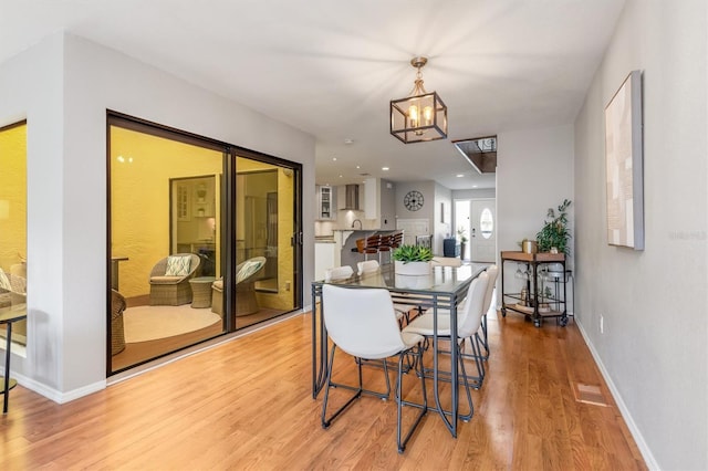 dining space with light hardwood / wood-style floors and an inviting chandelier