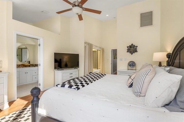 bedroom featuring ceiling fan, light hardwood / wood-style floors, vaulted ceiling, and ensuite bath