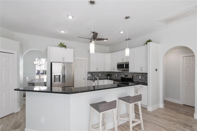 kitchen with white cabinetry, a kitchen island with sink, sink, stainless steel appliances, and ceiling fan with notable chandelier