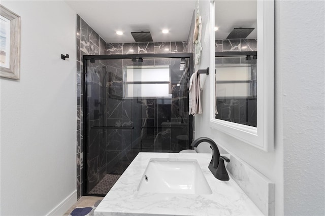 bathroom featuring a marble finish shower and vanity