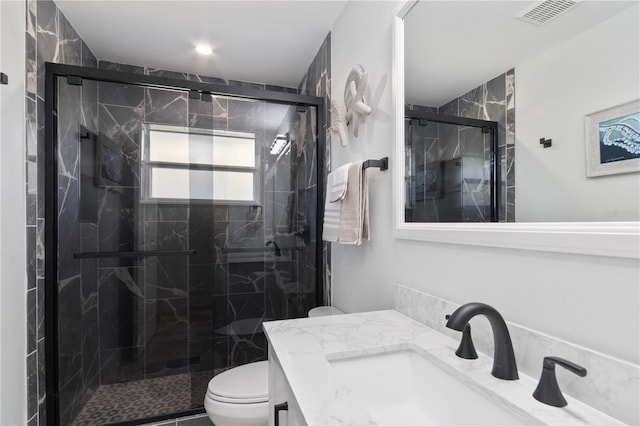 bathroom with toilet, a marble finish shower, visible vents, and vanity