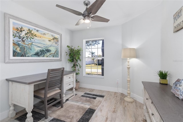 office space featuring baseboards, ceiling fan, and light wood-style floors