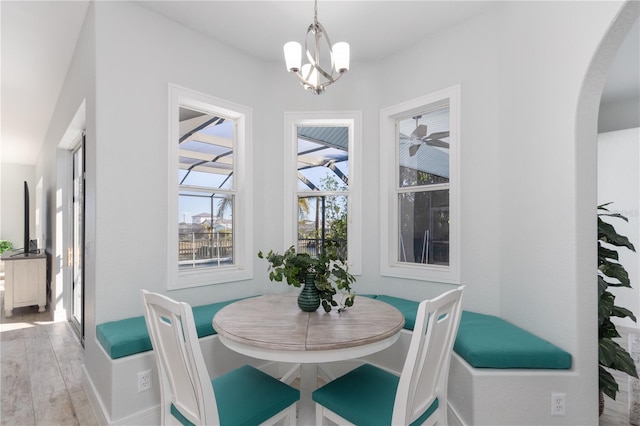 dining space with arched walkways, light wood-style flooring, and a notable chandelier