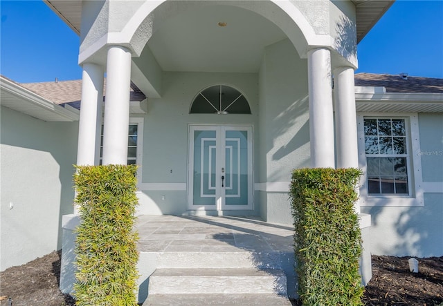 view of exterior entry featuring a shingled roof and stucco siding