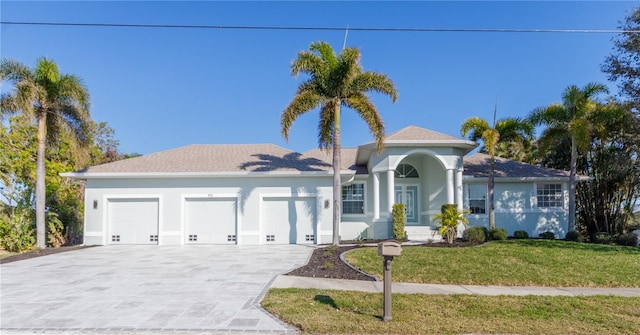 mediterranean / spanish house featuring a garage, concrete driveway, a front lawn, and stucco siding