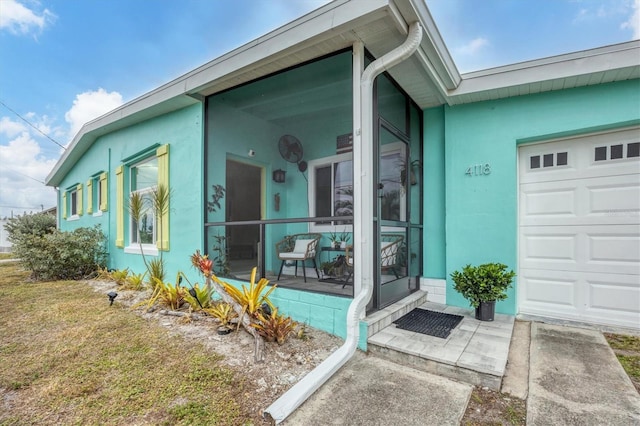 doorway to property featuring a garage and a lawn