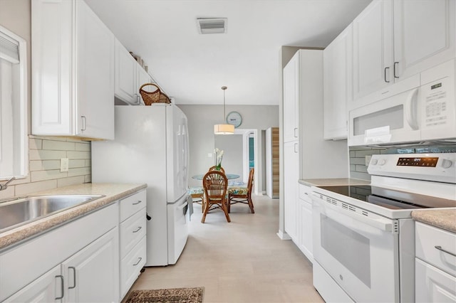 kitchen featuring white appliances, white cabinetry, decorative backsplash, sink, and hanging light fixtures