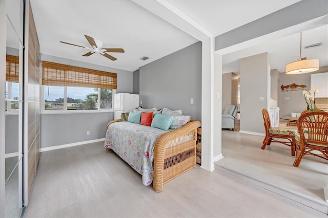 bedroom with ceiling fan, light hardwood / wood-style flooring, and white refrigerator