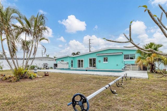 rear view of house with a patio area, a pool, and a yard